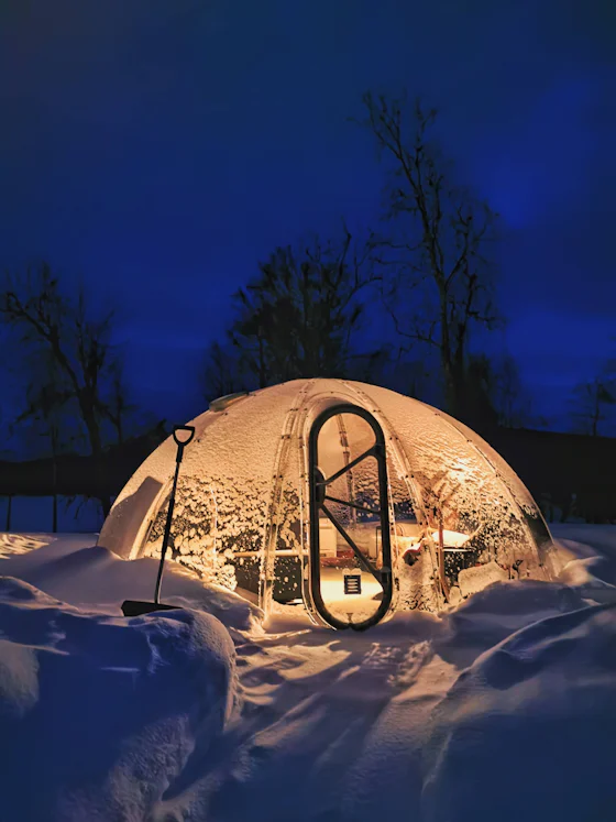 A glowing igloo at dusk in the snow
