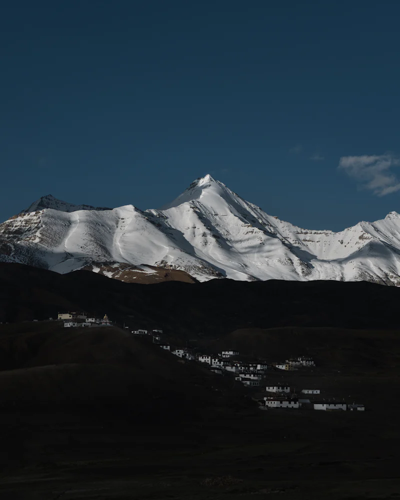 A colourful Buddha statue facing snow peaks in Spiti.